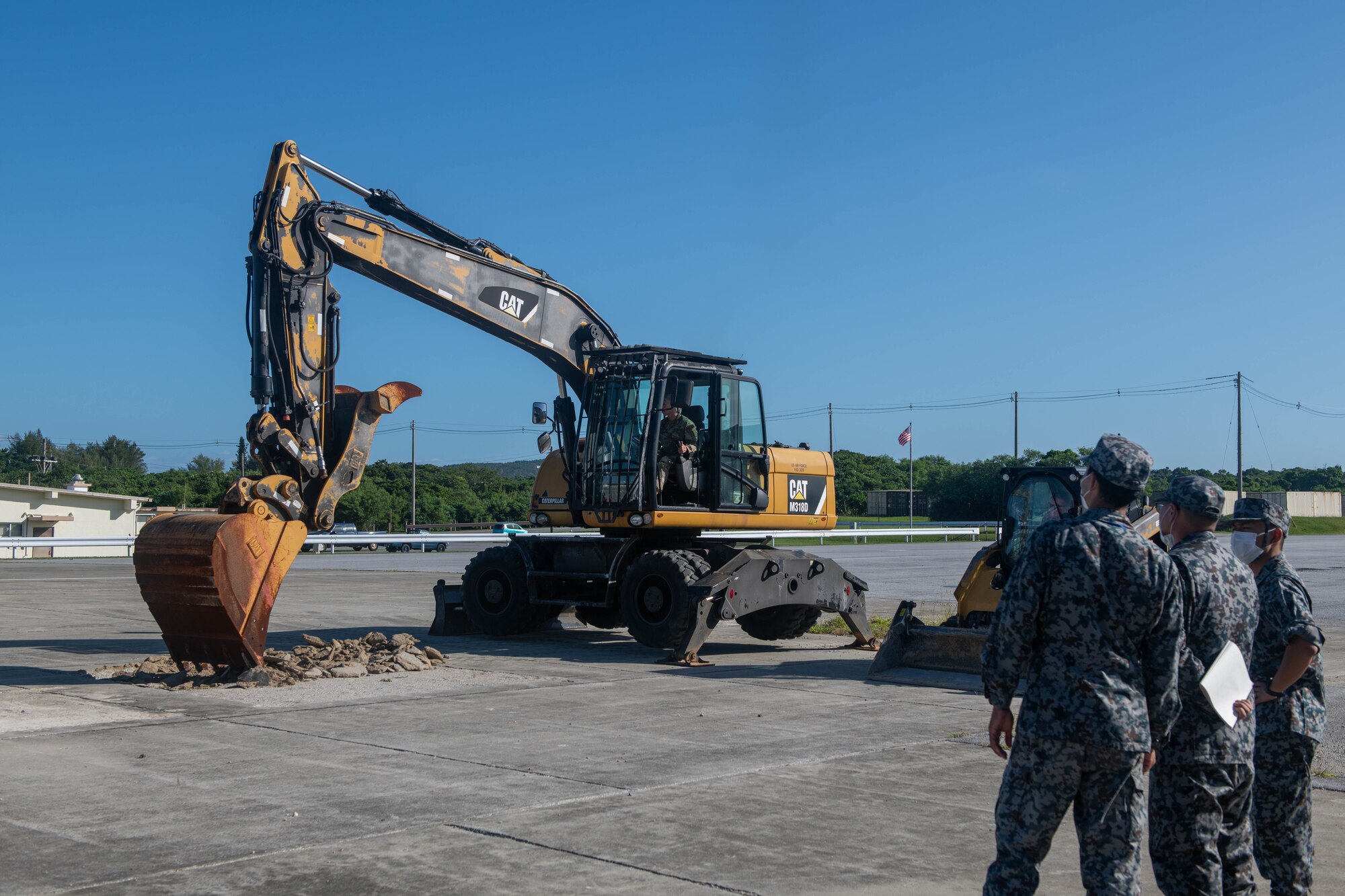 Japan Air Self-Defense Force members watch and excavator.