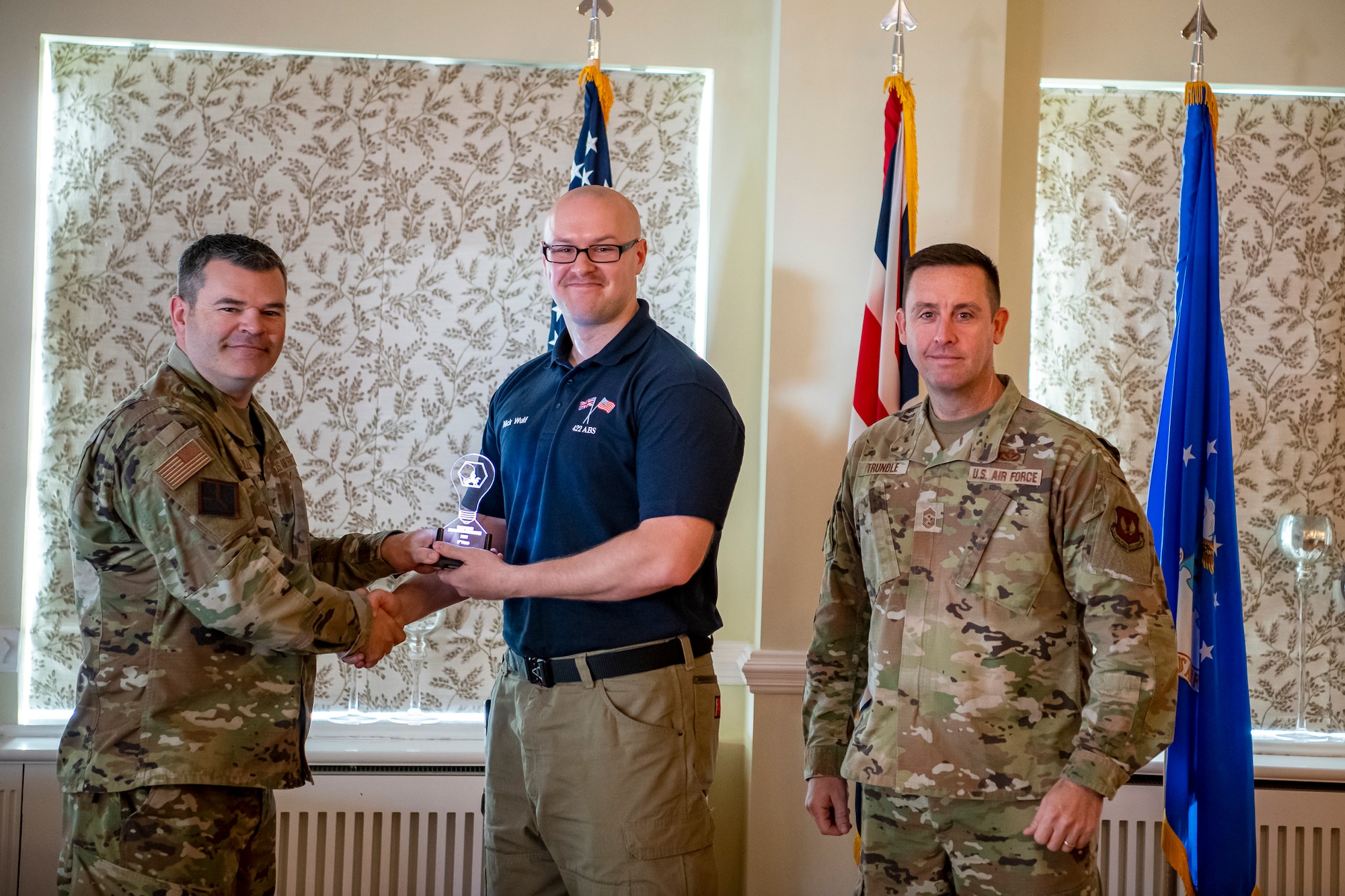 Nicholas Wulf, center, 422d Air Base Squadron supervisory logistics specialist, accepts an award from U.S. Air Force Col. Brian Filler, left, 501st Combat Support Wing commander and Chief Master Sgt. Joshua Trundle, 501st CSW command chief, during the Pathfinder Innovation Conference at RAF Alconbury, England, Oct. 21, 2022. The conference gave participants an opportunity to pitch their innovations, which were evaluated by a panel of judges and ranked based on their feasibility and overall benefit to the 501st Combat Support Wing mission. (U.S Air Force photo by Staff Sgt. Eugene Oliver)