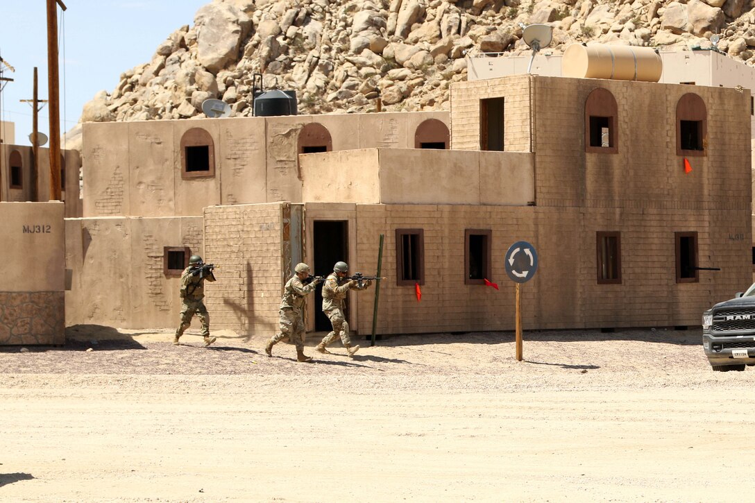 Three soldiers carrying weapons exit a building.