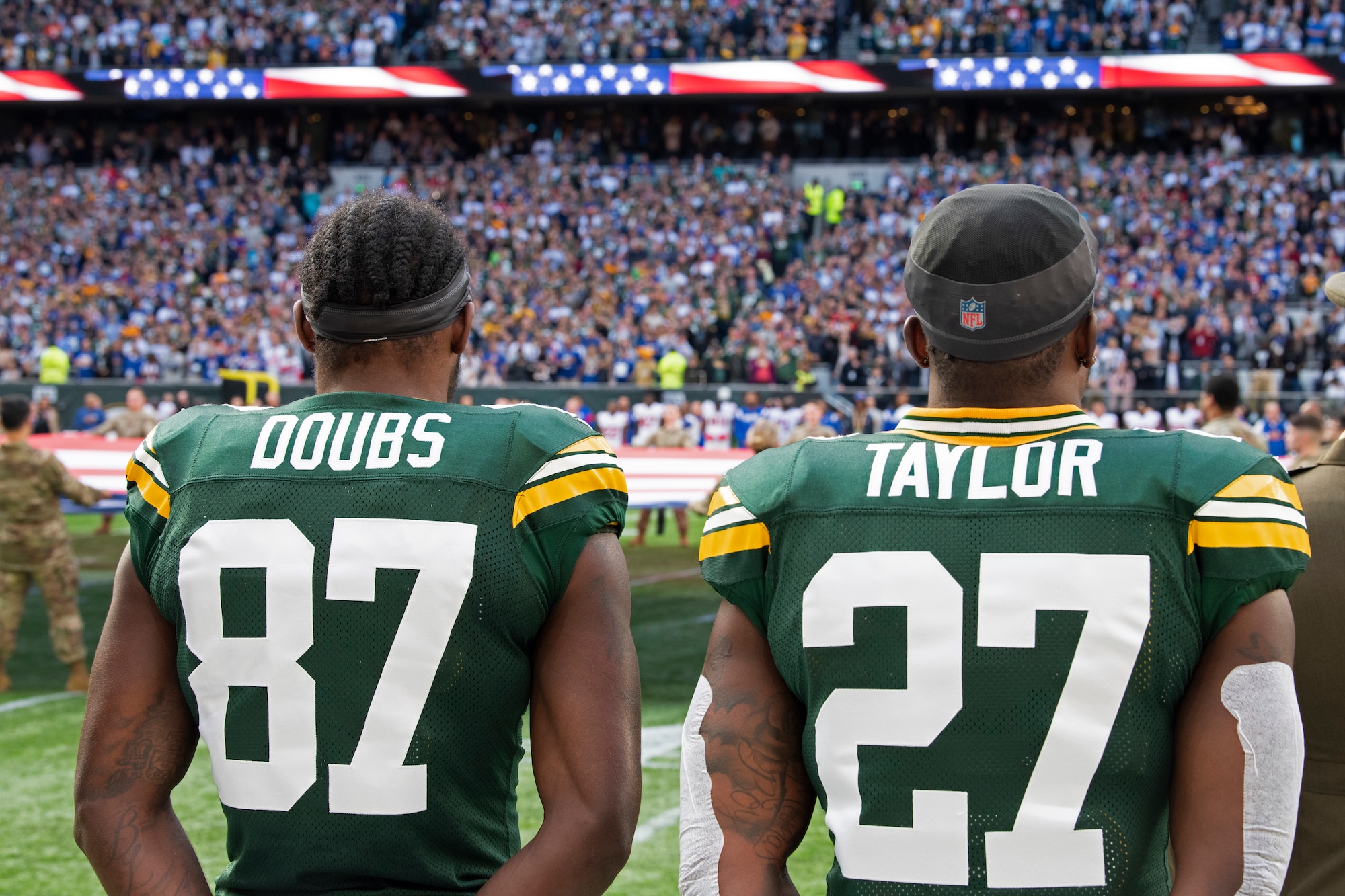 Romeo Doubs, Green Bay Packers wide receiver, and Patrick Taylor, Packers running back, stand on the sideline during the U.S. National Anthem of the National Football League’s New York Giants vs. Green Bay Packers game at Tottenham Hotspur Stadium, in London, England, Oct. 9, 2022. The pre-game ceremony featured more than 50 Airmen unfurling the flag along with an honor guard team and vocalist to sing the U.S. National Anthem. (U.S. Air Force photo by Tech. Sgt. Anthony Hetlage)