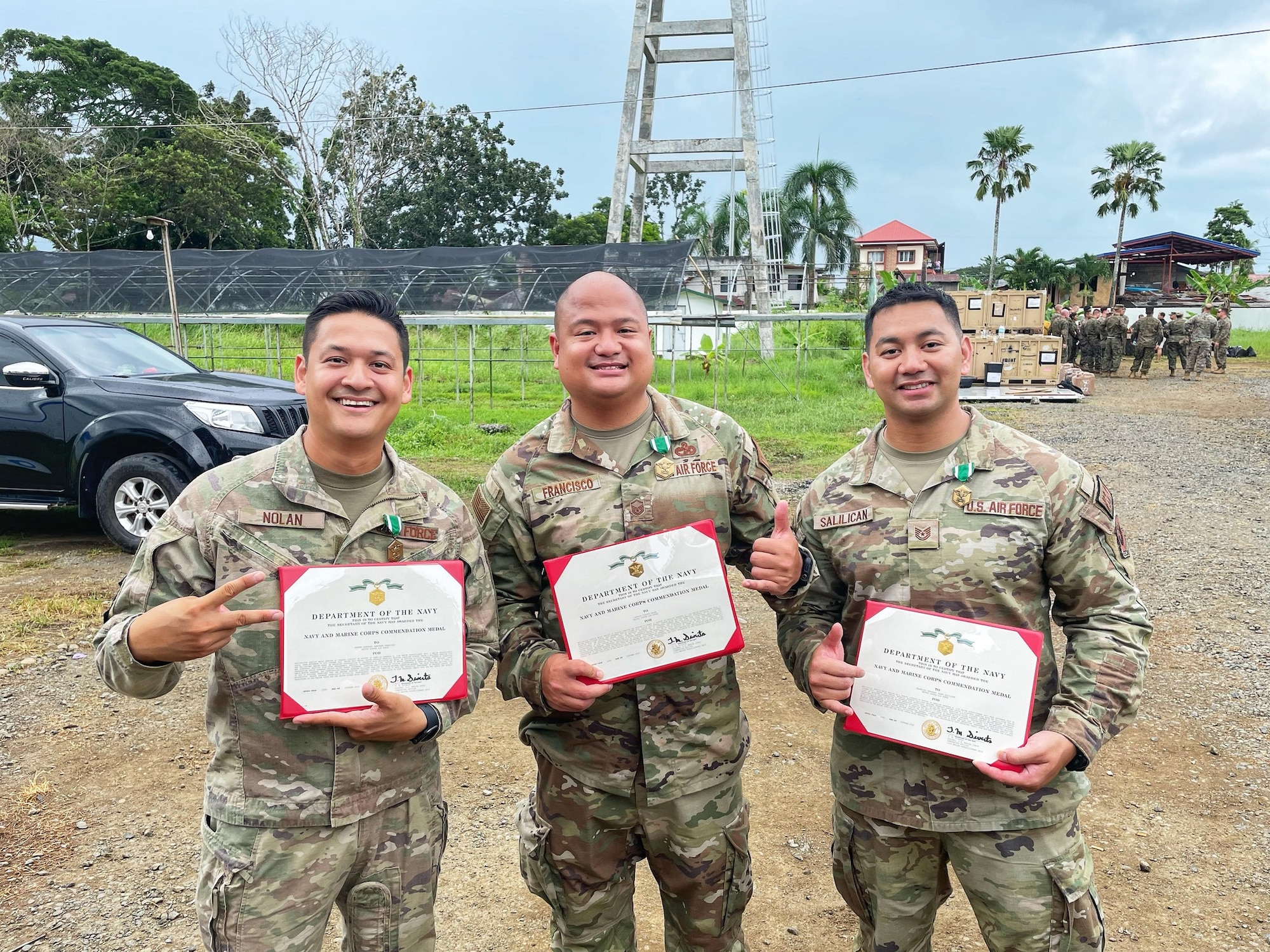 Three Airmen posing with Marine Corps Commendation Medal Certificates