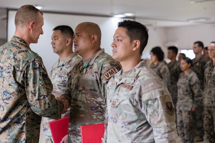 Three Airmen receiving Navy and Marine Corps Commendation Medals