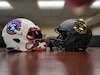 a white football helmets sits on a table facing a black football helmet