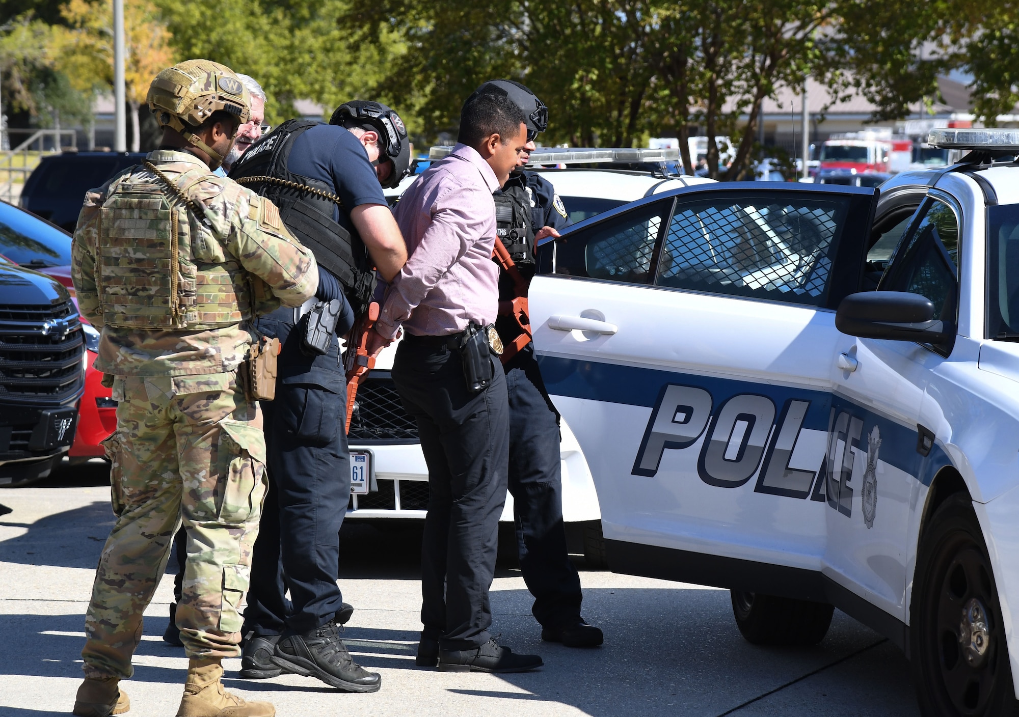 Members of the 81st Security Forces Squadron prepare to place Detective Mark Wood, Gulfport Police Department detective who portrays an active shooter, inside a police car during an active shooter exercise outside the Levitow Training Support Facility at Keesler Air Force Base, Mississippi, Oct. 20, 2022.