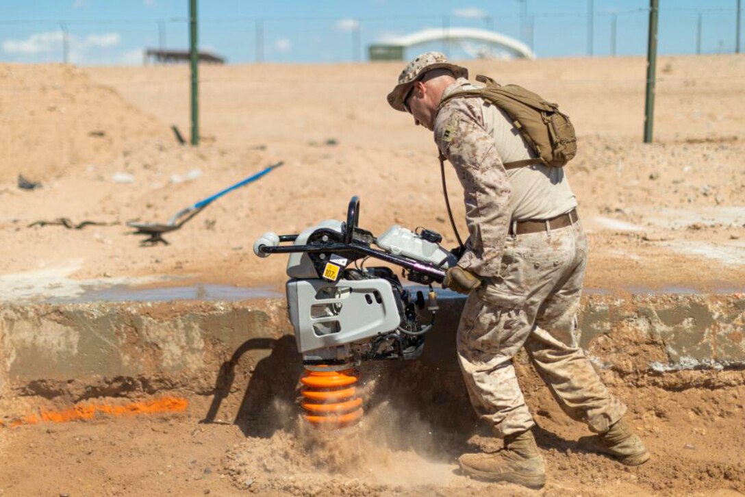 A Marine uses a plate compactor to compress to dig in the dirt.