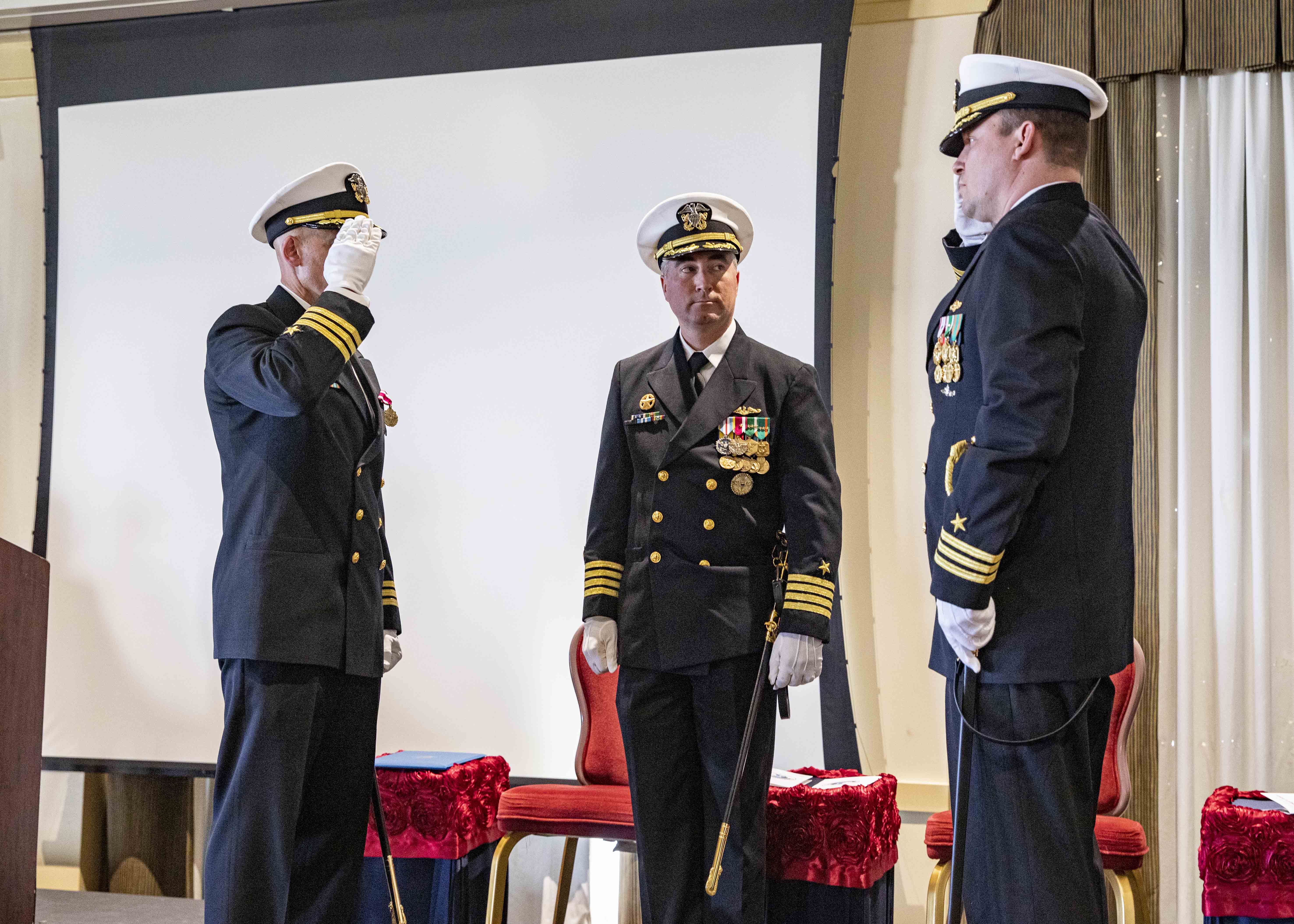 Capt. Brian Hogan, commodore, Submarine Squadron Eight, center, watches as Cmdr. Christopher Holland, right, relieves Cmdr. Jonathan Cantor, left, as commanding officer of the Los Angeles-class attack submarine USS Boise (SSN 764) during a change of command ceremony onboard Naval Station Norfolk, Oct. 21, 2022.