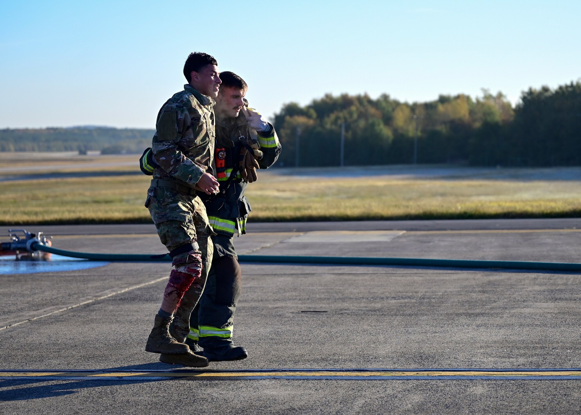 A firefighter carries an Airman by the shoulder.