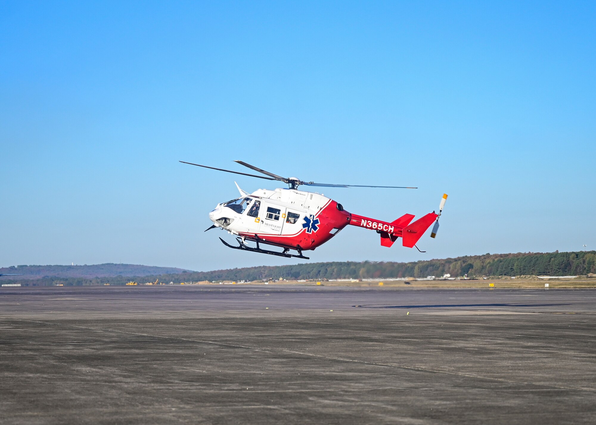 A helicopter lands on a flightline.