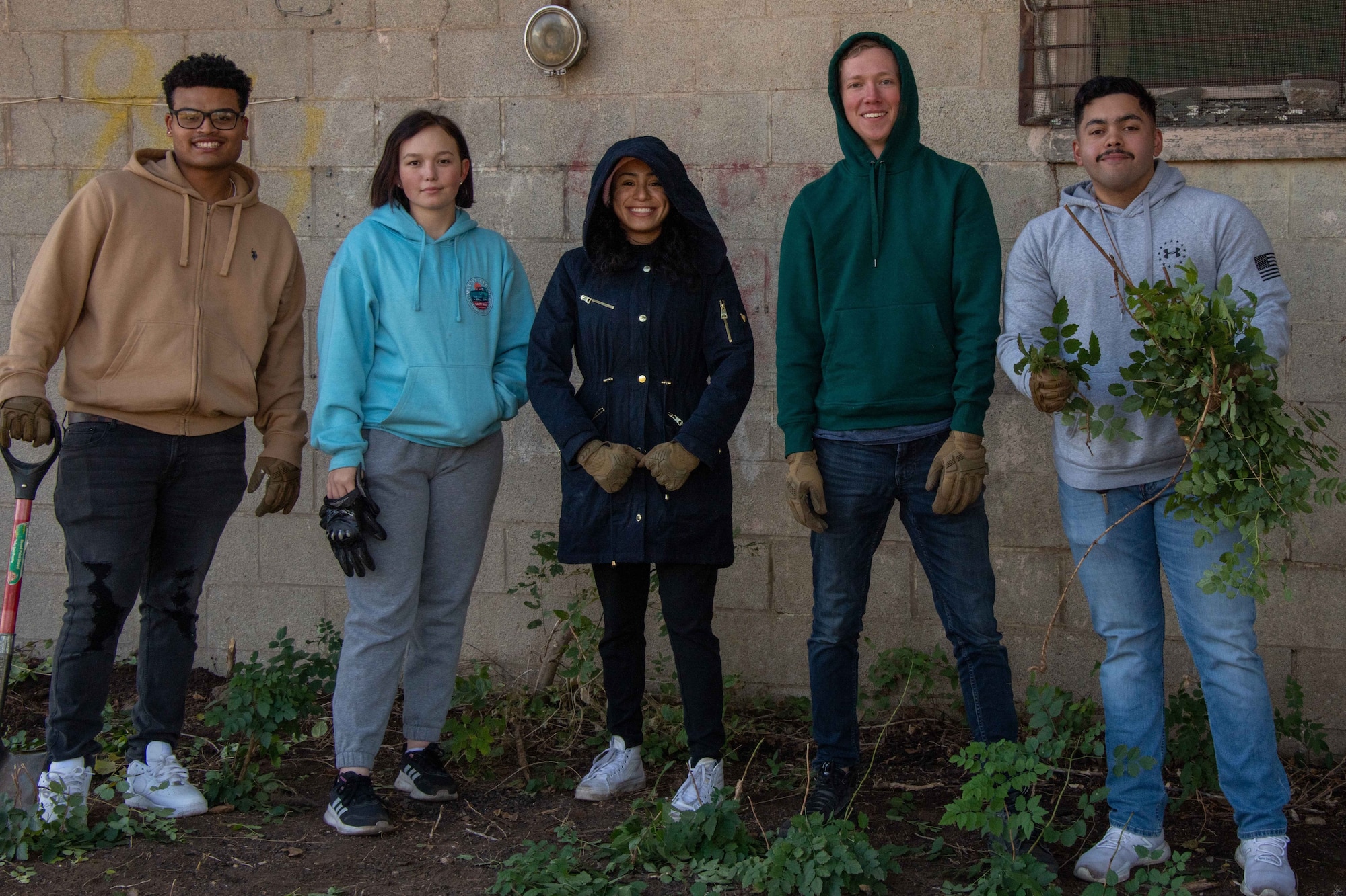 Airmen from the 97th Security Forces Squadron pose for a photo while helping to restore and beautify a building lot in Altus, Oklahoma Oct. 19, 2022. The community service project is meant to build the social and spiritual aspects of the Airmen while bringing them together with other community members. (U.S. Air Force photo by Airman 1st Class Kari Degraffenreed)