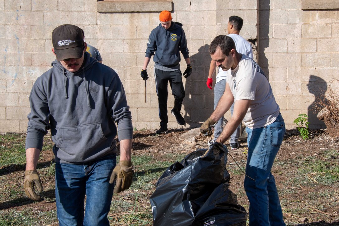Airmen from the 97th Security Forces Squadron (SFS) pull weeds and pick up trash at an abandoned building lot in Altus, Oklahoma Oct. 19, 2022. The 97th SFS also invites Airmen from other squadrons to be a part of the standard resiliency course and exercise their comprehensive Airman fitness. (U.S. Air Force photo by Kari Degraffenreed)