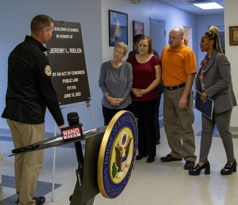 The family of fallen Illinois Army National Guard Spc. Jeremy Ridlen, mother, Cheryl, sister, Amanda and twin brother, Jason, join U.S. Congressman Rodney Davis and Bernice Joseph, customer relations manager, U.S. Postal Service, during the unveiling of the plaque, dedicating the Maroa, Illinois, post office in honor of Ridlen, during a ceremony Oct. 25 at the Maroa Fire Department.