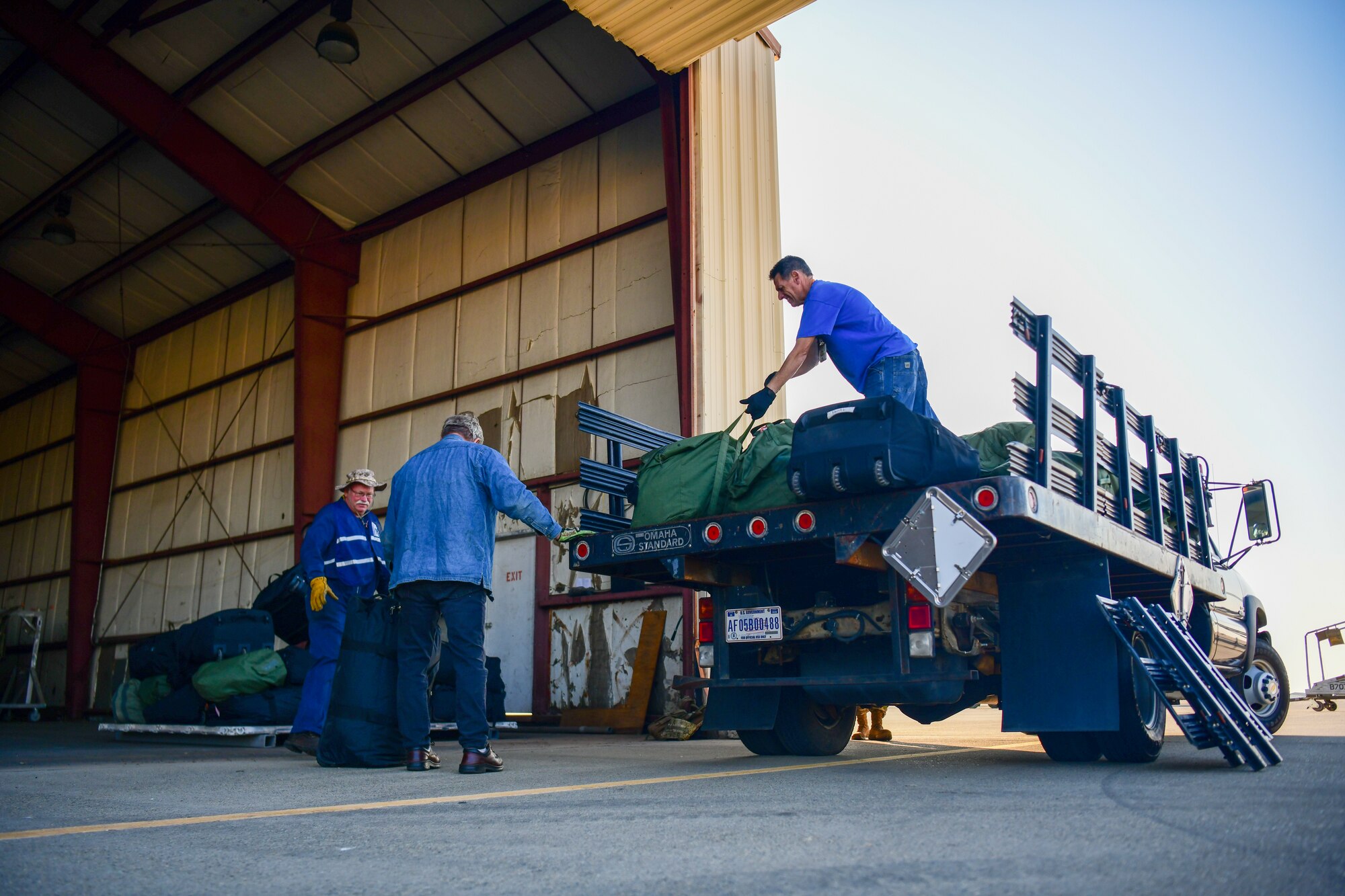 Civilians work together load equipment on to a pallet during an exercise