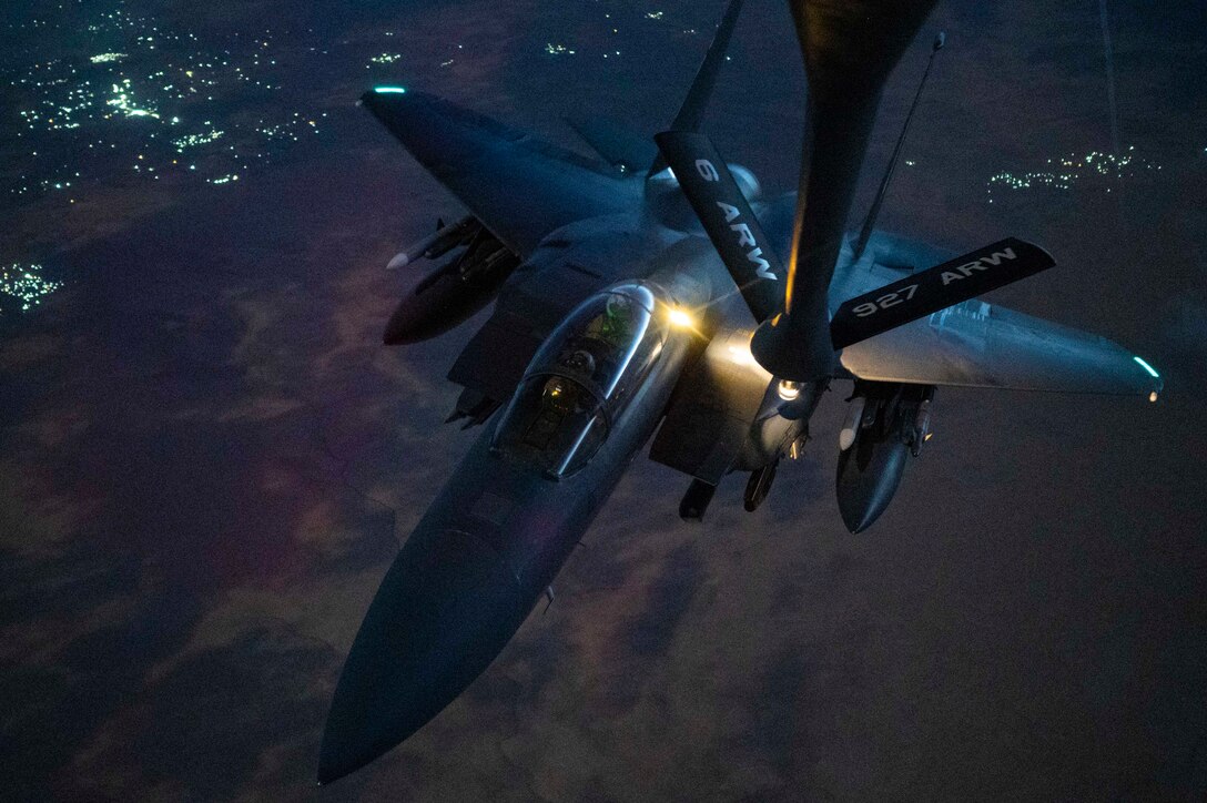 The arm from a refueling aircraft connects to another midair at night.