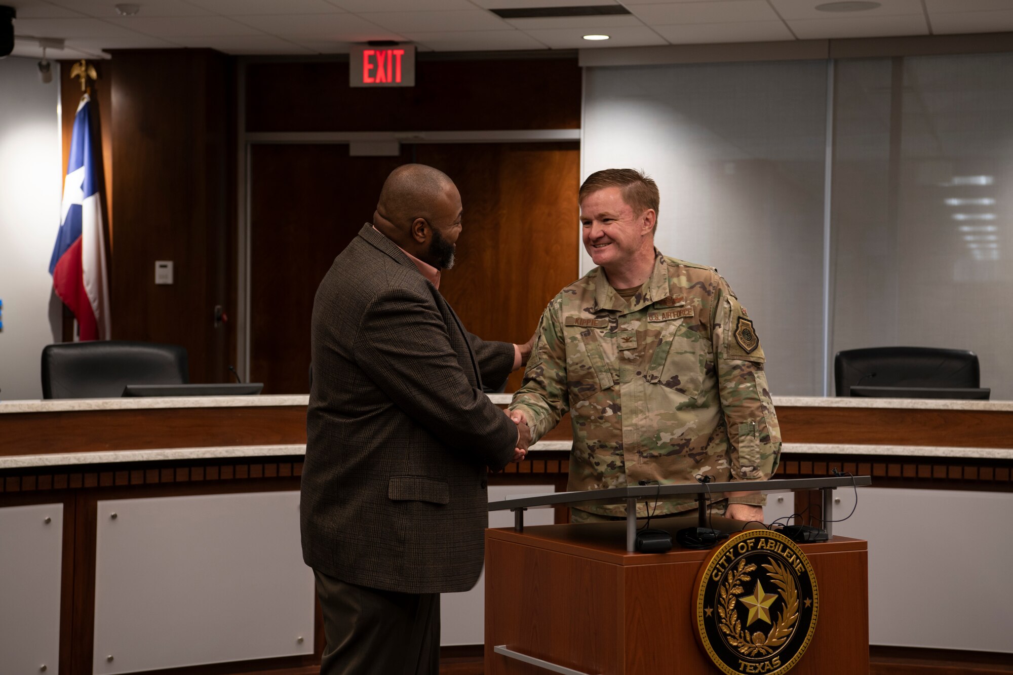 Two men shake hands behind a podium.