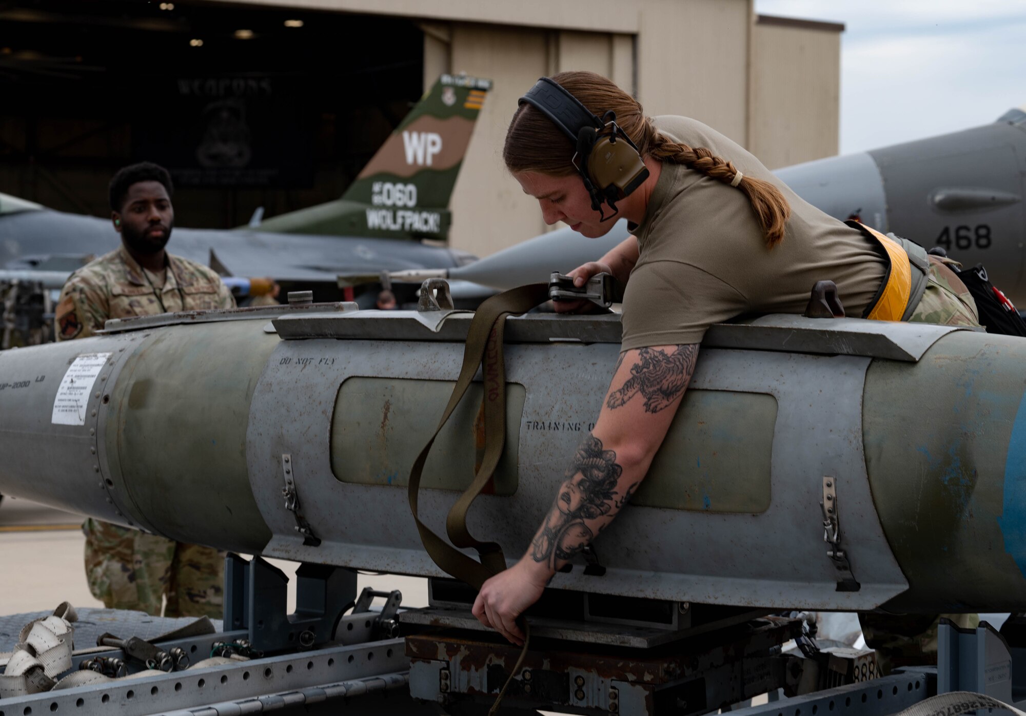 80th Fighter Generation Squadron weapons load crew member, secures a GBU-38 bomb