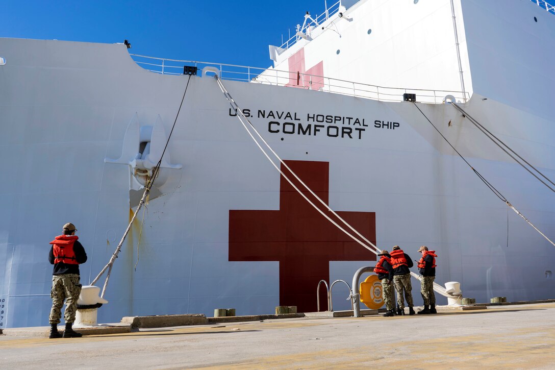 Sailors prepare to release the mooring lines from a hospital ship.