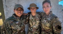 Three Airmen stand next to each other with arms wrapped around each other's shoulders.