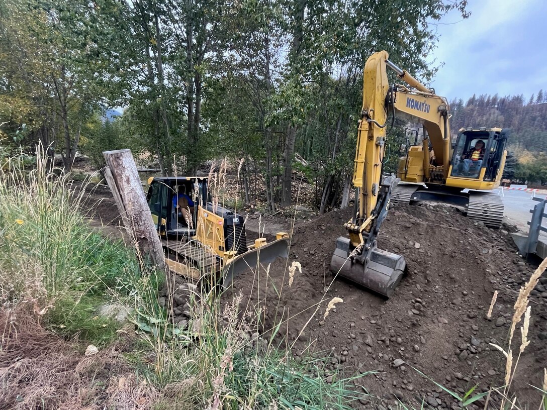 Photo of a man operating a bulldozer extracting dirt from Salmon Creek, a creek in the town of Conconully, in Okanogan County, in Washington State.