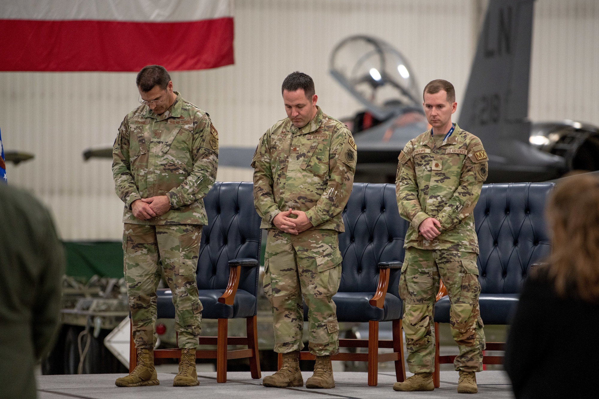 U.S. Air Force Col. Joseph Stangl, Maj. Steve Ortner, and Maj. Nathan Stroupe, commander of the 492nd Fighter Generation Squadron, right, bow their heads in prayer.