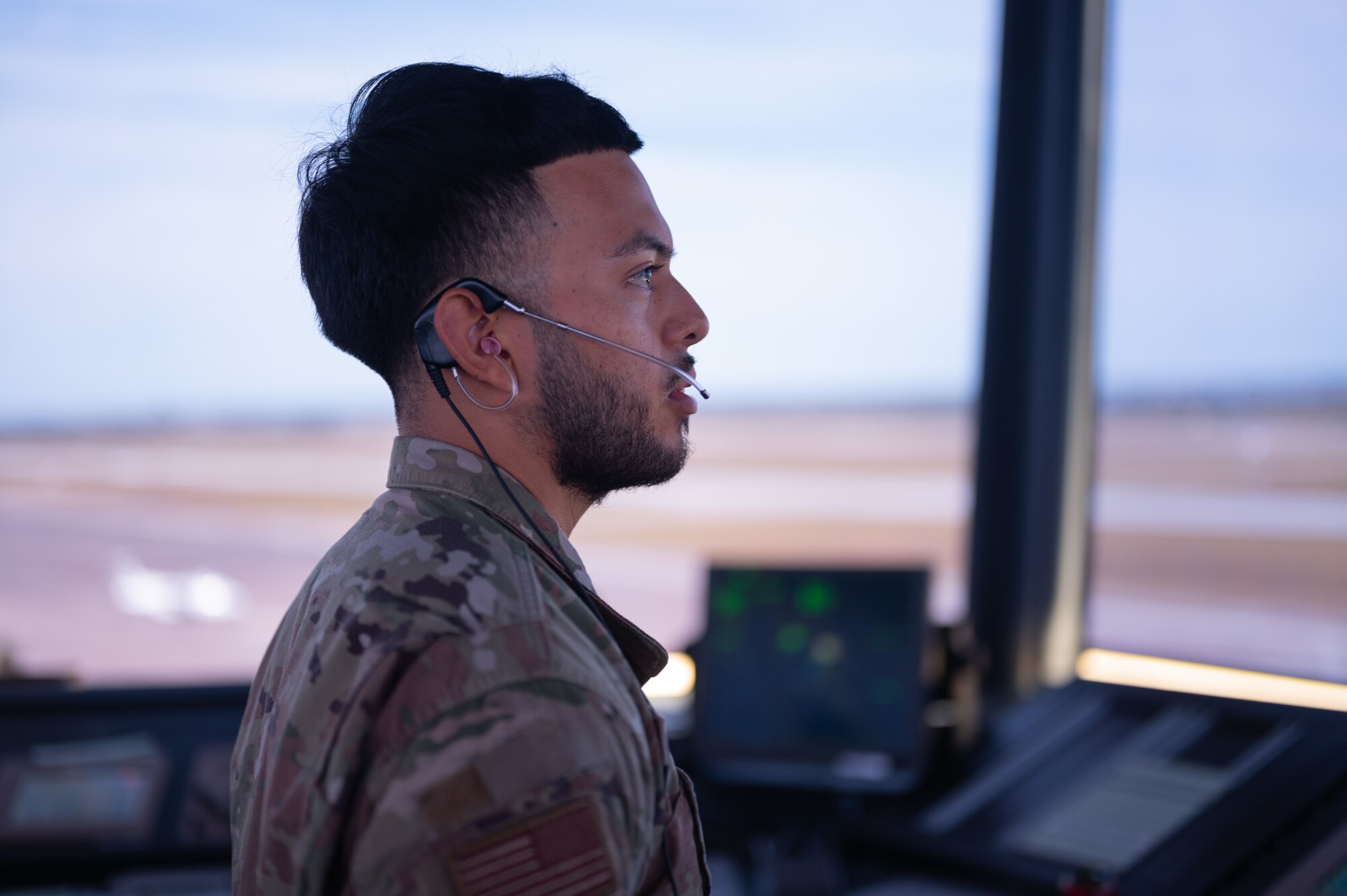 An Airman looks out on to the flight line from an air control tower.