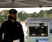 Beareded man in ball cap and sunglasses speaking and referring to an information board fo the Lynnhaven River Ecosystem Restoration Project while standing under a tent and trees in the background