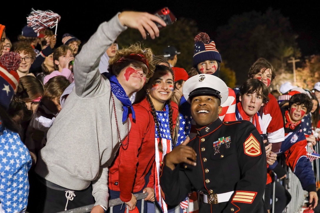 Students from Grosse Pointe South High School take a photo with U.S. Marine Corps Staff Sgt. Danta Coffey, a recruiter with Recruiting Station Cleveland, during a Great American Rivalry Series game in Madison Heights, Michigan, Oct. 22, 2022. Recruiters conducted a pull-up challenge, passed out t-shirts and presented scholarships to the students of the two schools. (U.S. Marine Corps photo by Cpl. Austin Fraley)