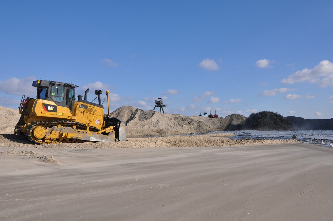 A bulldozer pushes sand on a beach