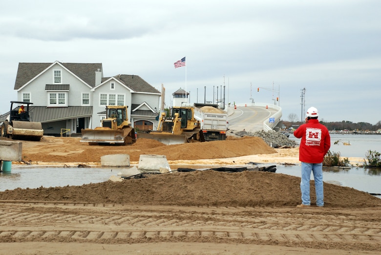A man in U.S. Army Corps of Engineers emergency response clothes looks at the site of levee repair.
