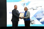 Male presenting female with award certificate on stage.