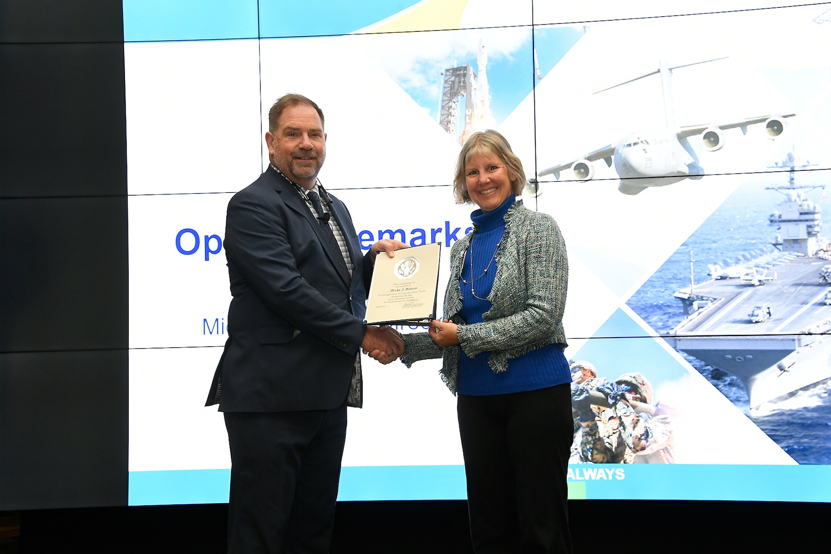 Male presenting female with award certificate on stage.