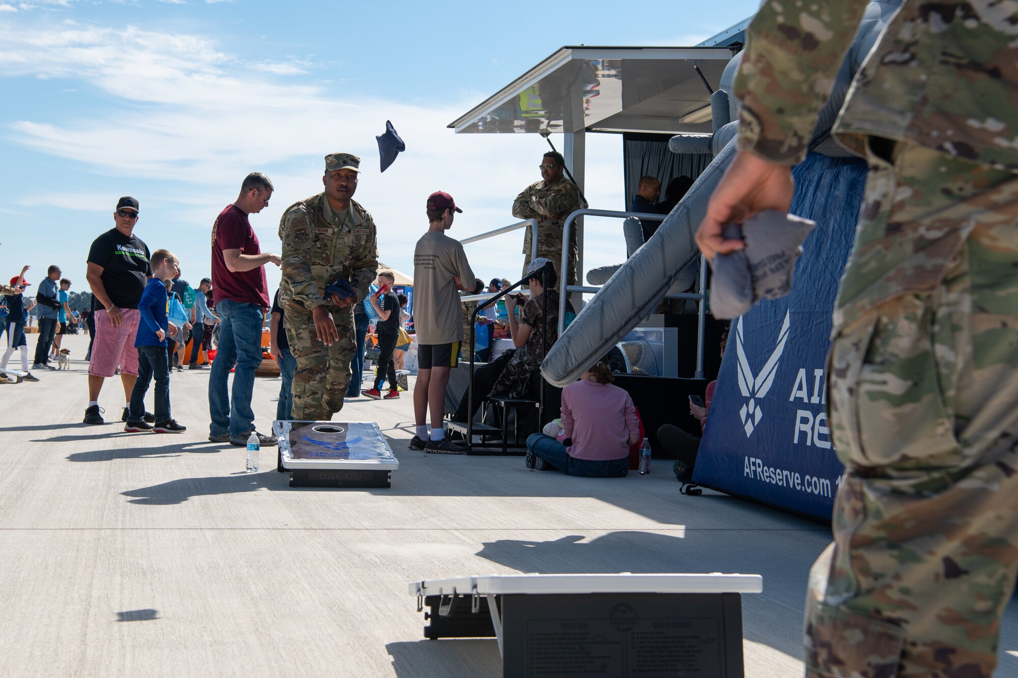 Servicemembers throw beanbags while playing cornhole.