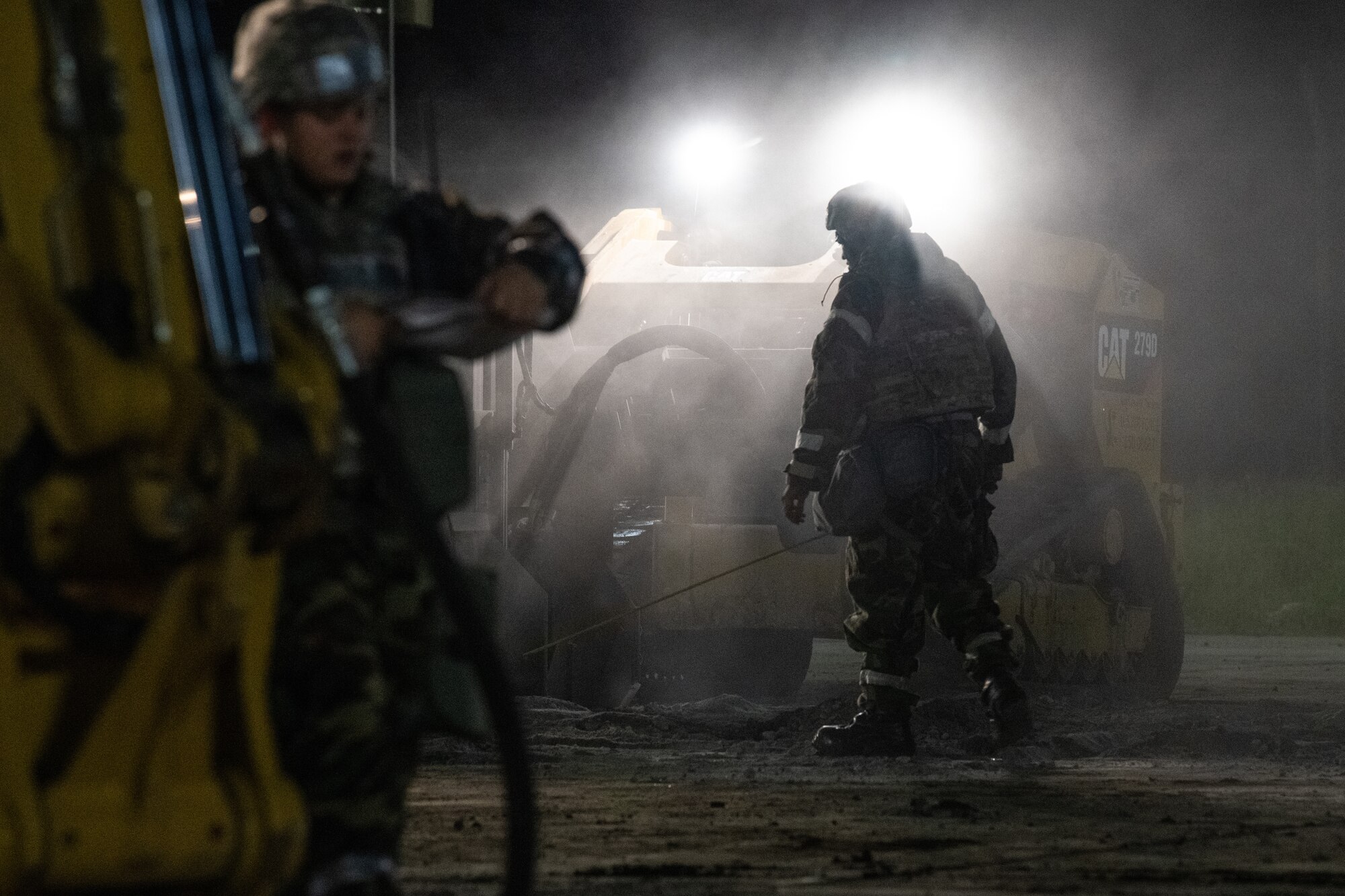 a airman in a protective suit stands in front of a bulldozer