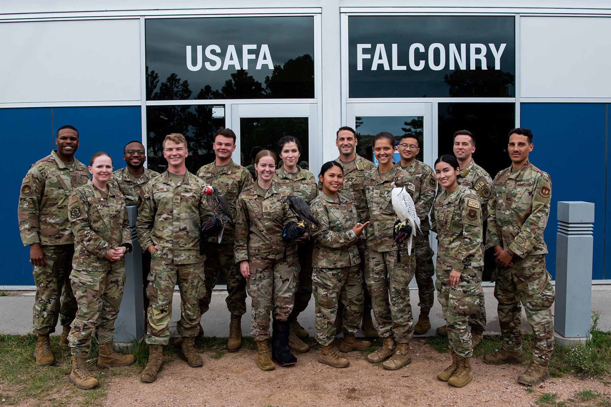 Cadets from the falconry club pose for a photo with members of the 12 Outstanding Airmen of the Year