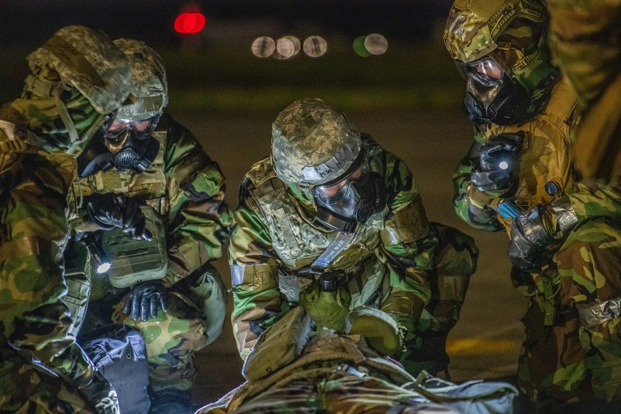 three medics in protective suits treat an injured dummy on the flightline
