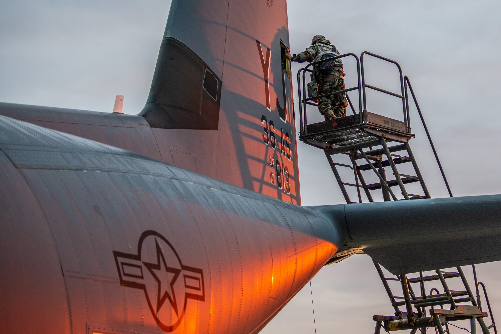 two airmen are lifted to the tail of a large airplane