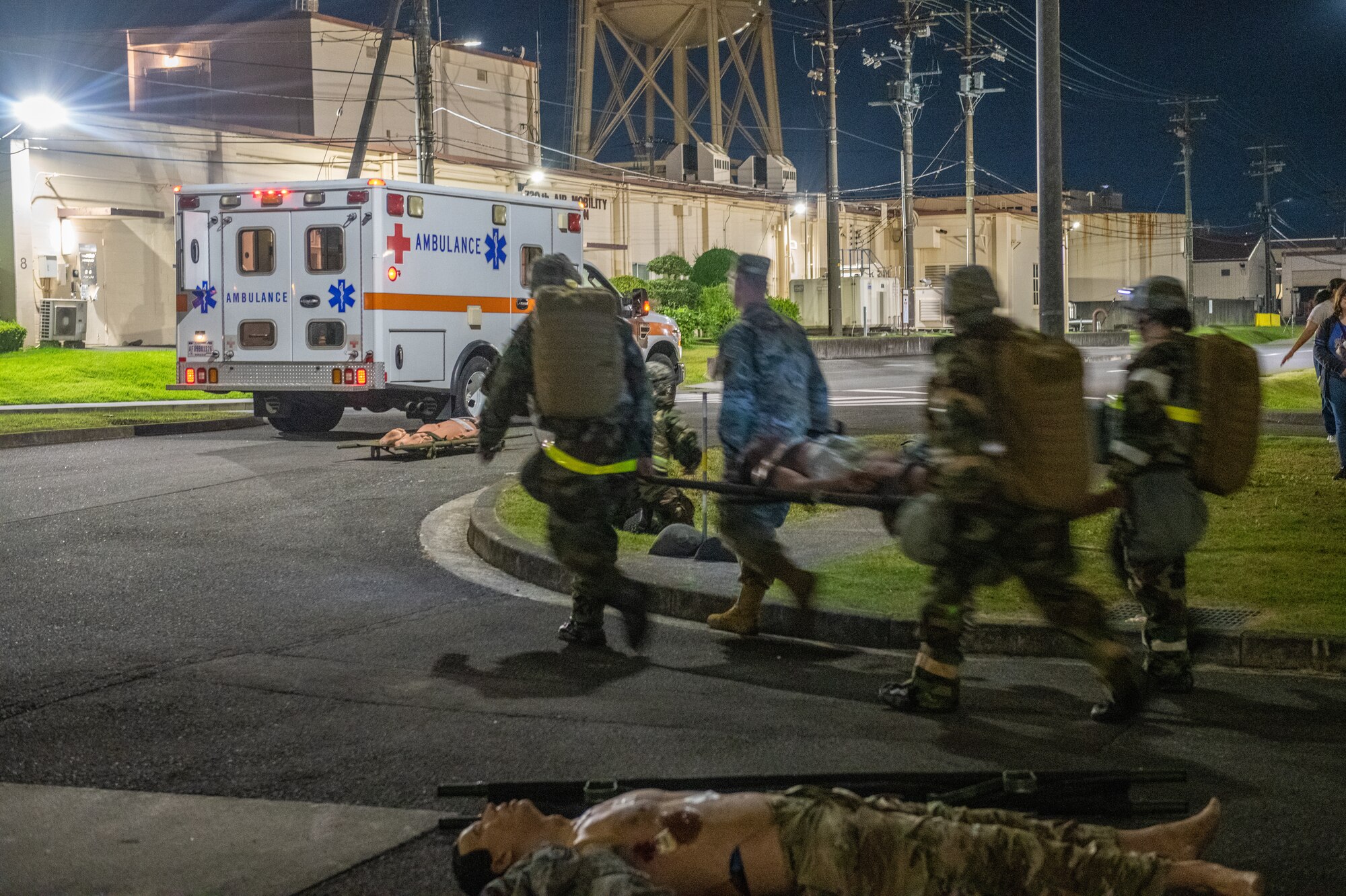 four medics in protective gear carry a stretcher to an ambulance