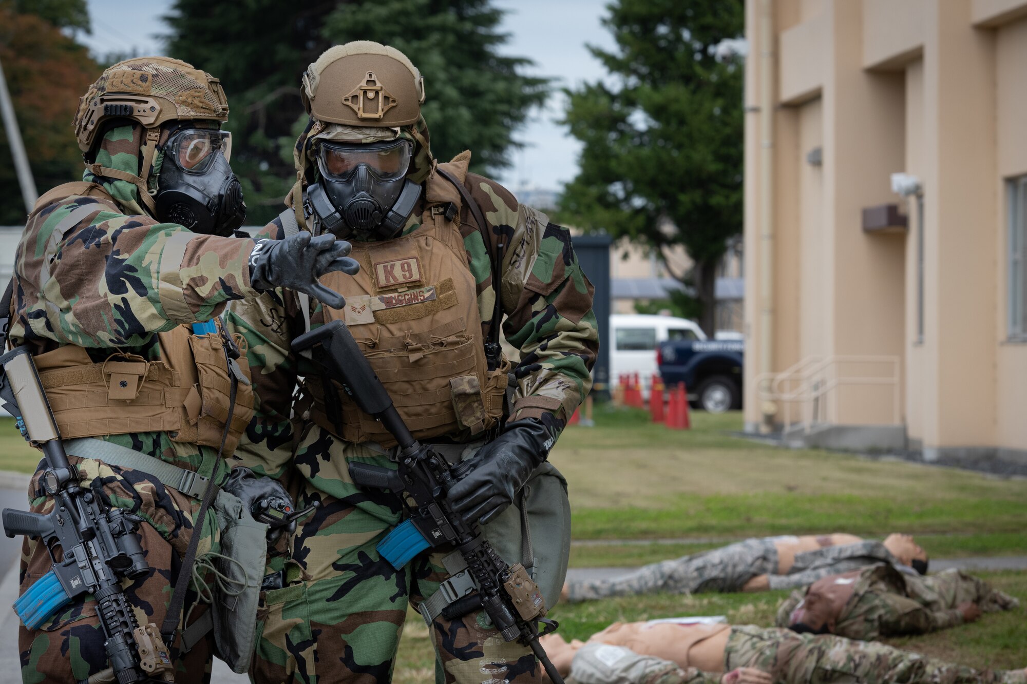 Two Airmen talk through gas masks