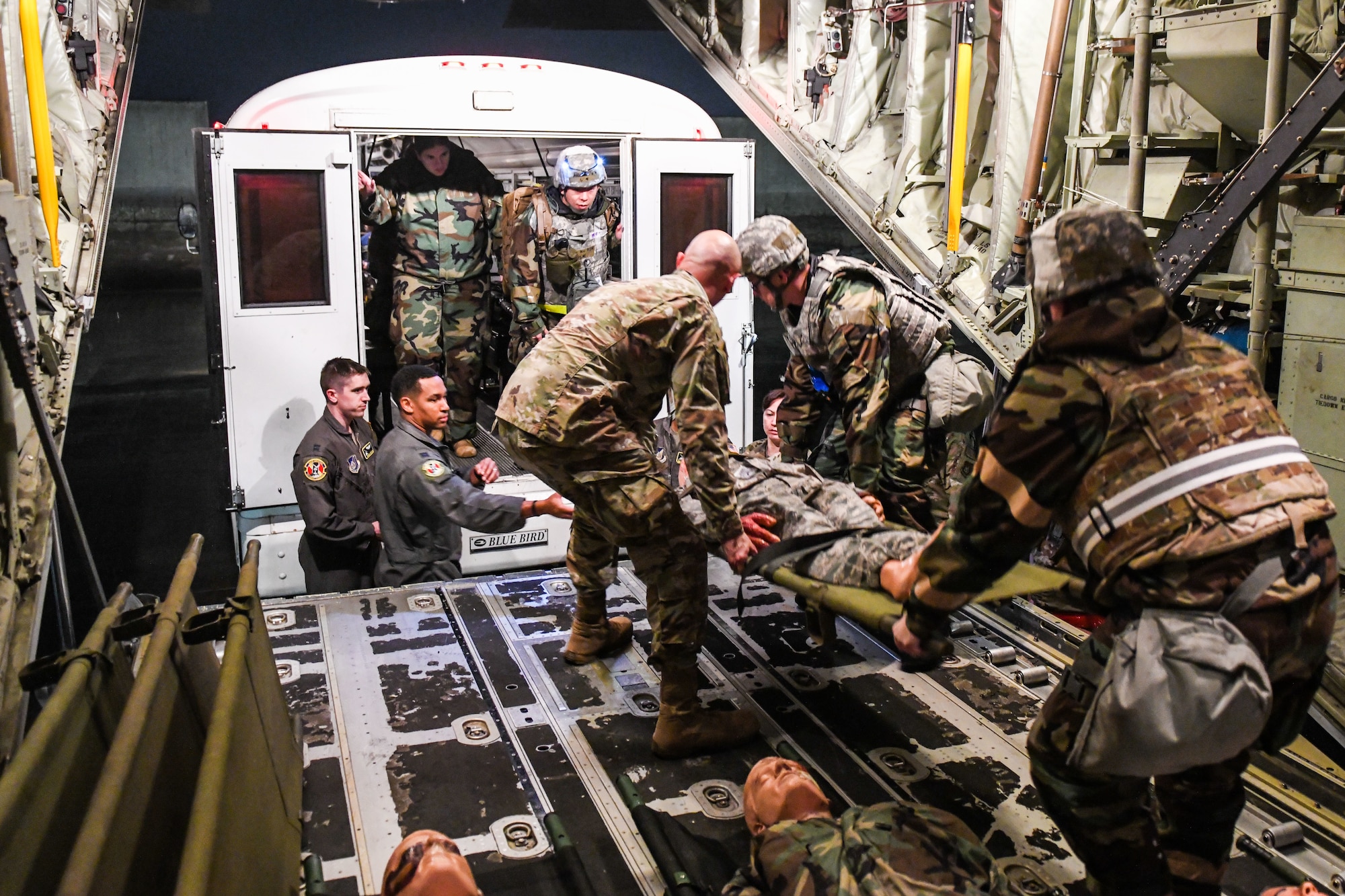 several airmen move injured on stretchers from a plane to a bus