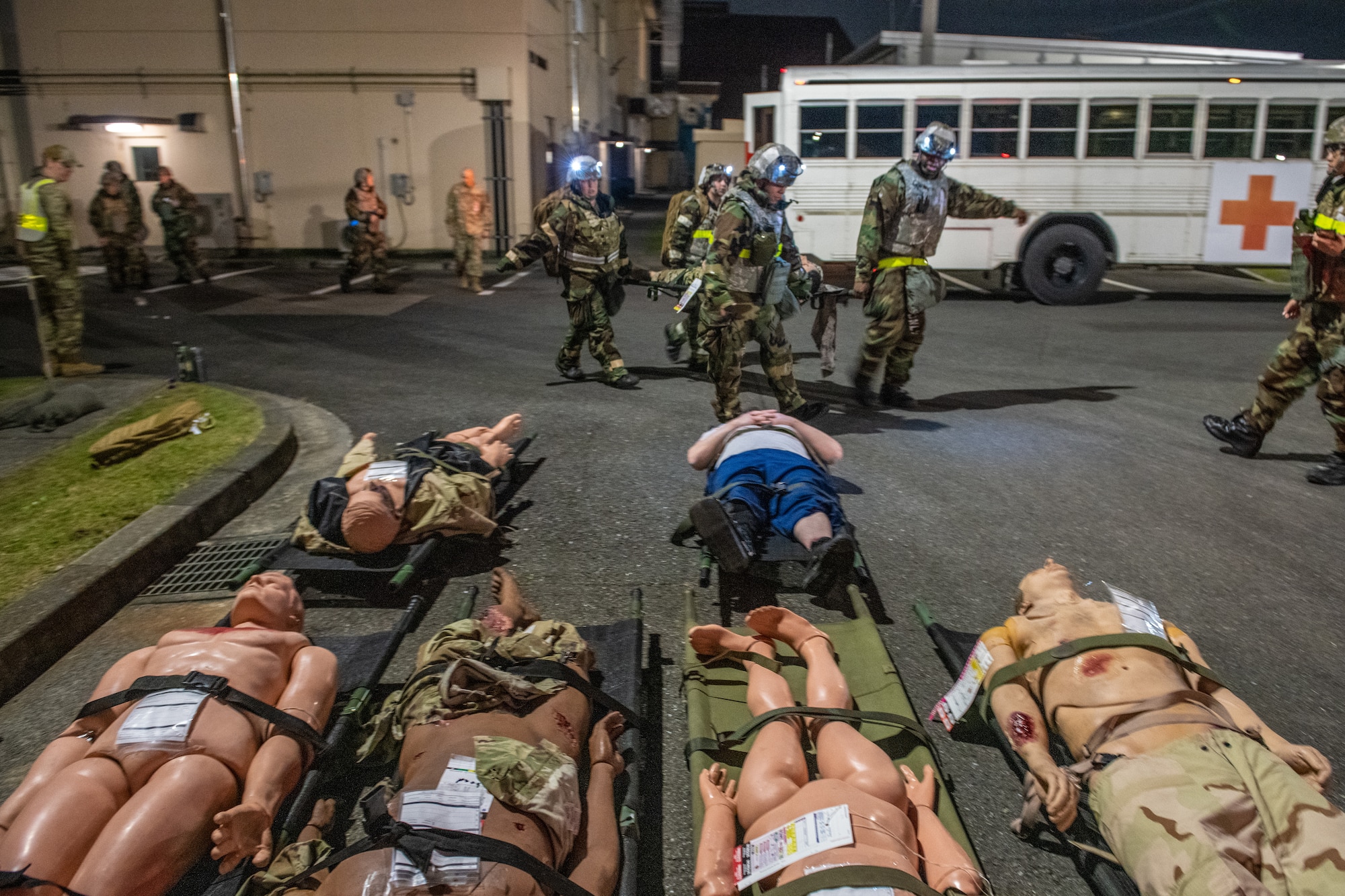 a medical bus in front of several stretchers on the ground with dummies