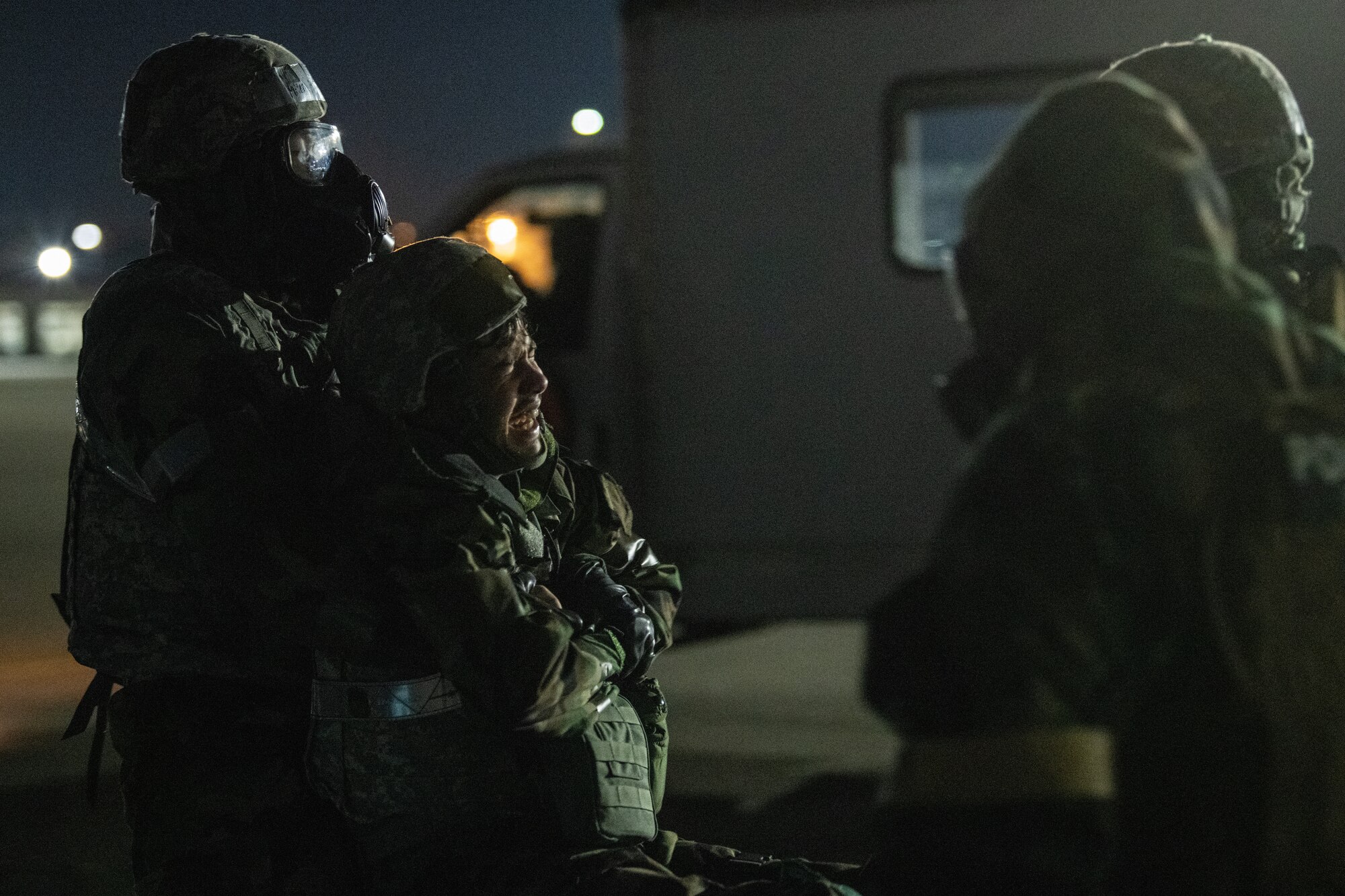nighttime on the flightline as three airmen fireman carry a fourth to safety