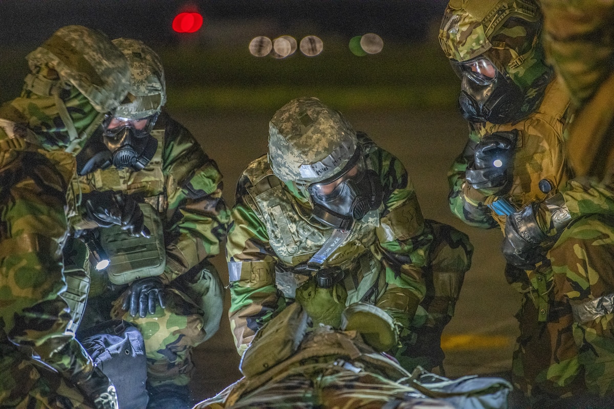 three medics in protective suits treat an injured dummy on the flightline