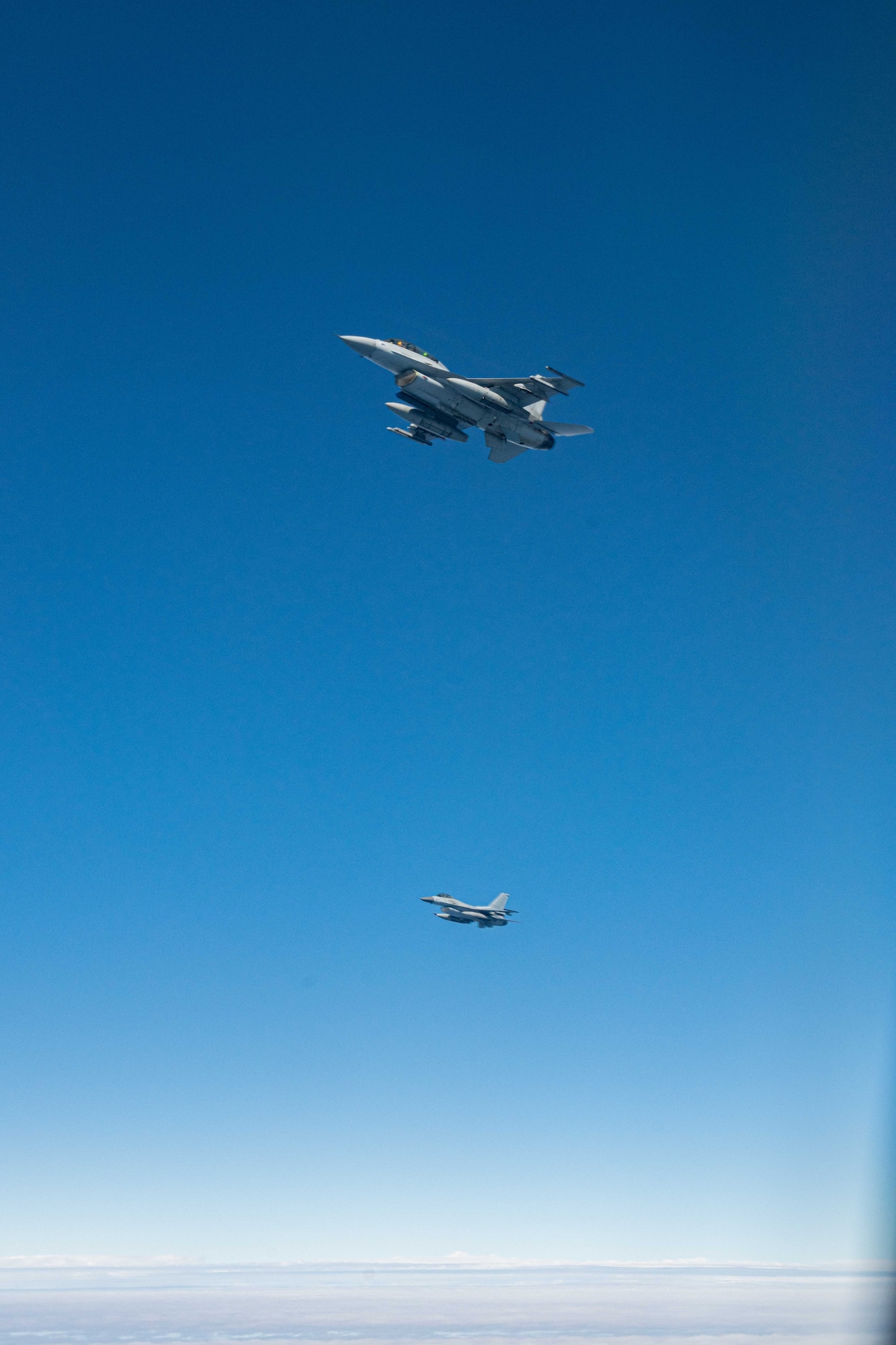 Two F-16s fly in the blue sky