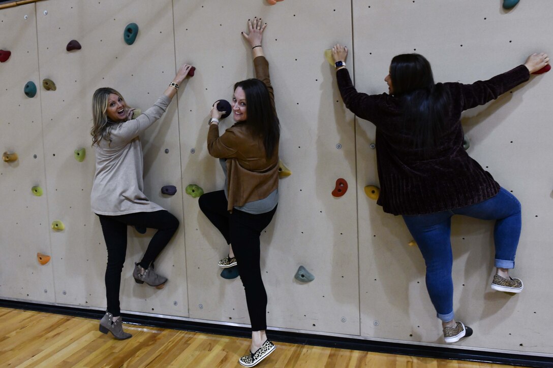 Leadership spouses from the 97th Air Mobility Wing climb a rock wall at the Youth Center at Altus Air Force Base, Oklahoma, Oct. 19, 2022. The Youth Center provides engaging activities for youth ages five to 18 years old and is open year-round for school age children. (U.S. Air Force photo by Airman 1st Class Miyah Gray)