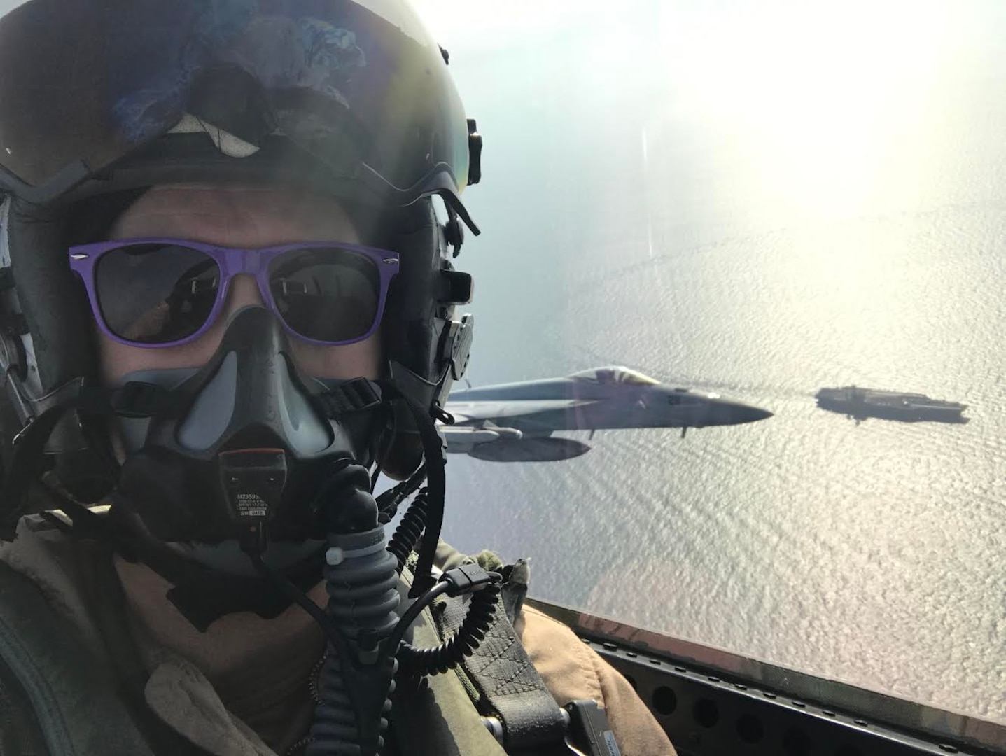 Pilot wearing purple sunglasses takes selfie in jet