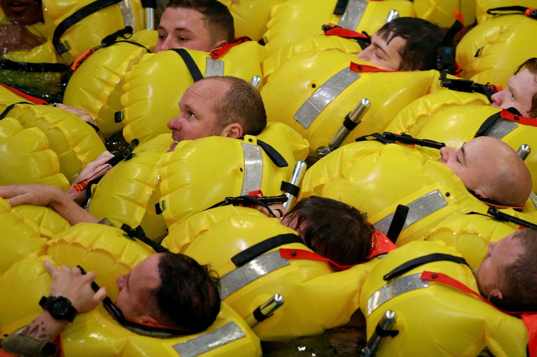 Soldiers lay next to each other in yellow life vests.