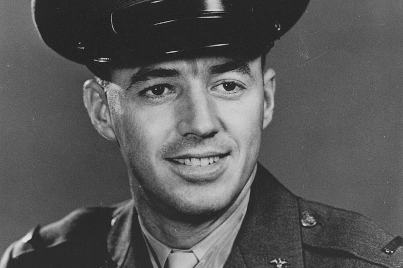 A man carries a small child in his arms as a woman carrying flowers walks beside him.