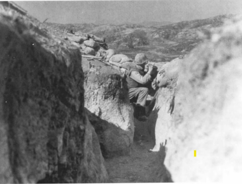 A man squats down in a 3-foot trench.