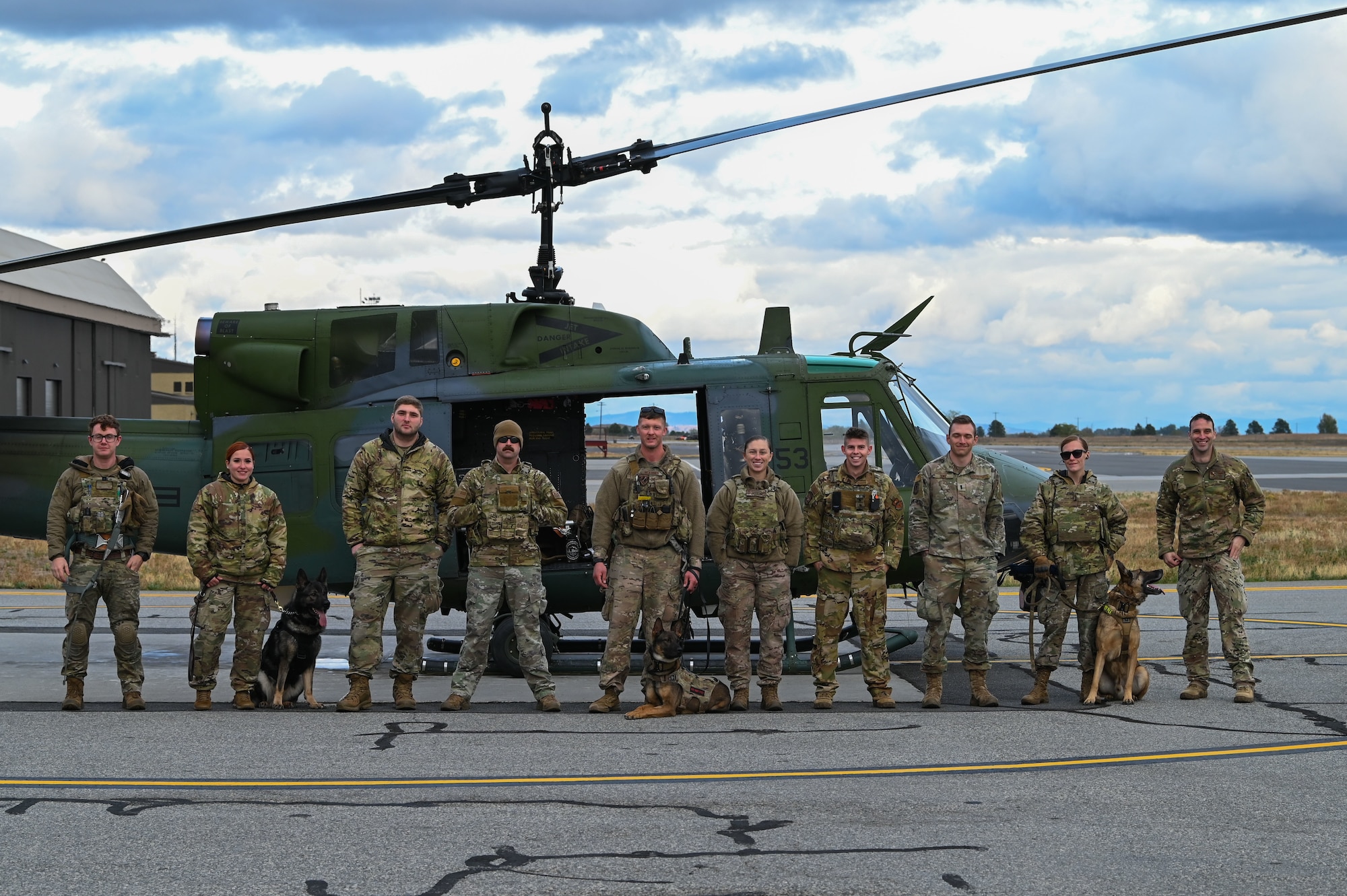 U.S. Air Force Military Working Dog handlers from the 92nd Security Forces Squadron pose for a photo after completing helicopter familiarization training at Fairchild Air Force Base, Washington, Oct 25, 2022. The purpose behind the helicopter training was to expose MWD's to new noises they might hear when boarding and flying on a helicopter. (U.S. Air Force photo by Airman 1st Class Stassney Davis)