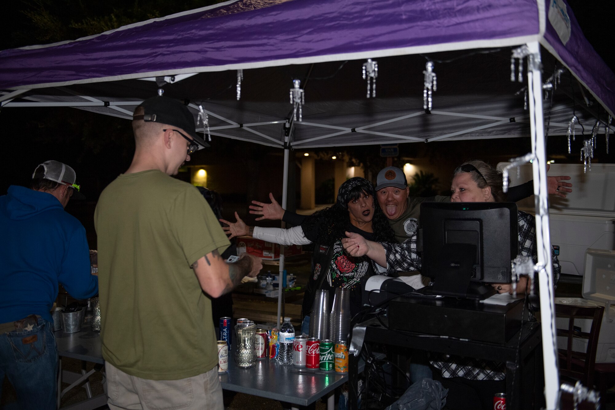 A photo of three people handing out refreshments standing under a tent.