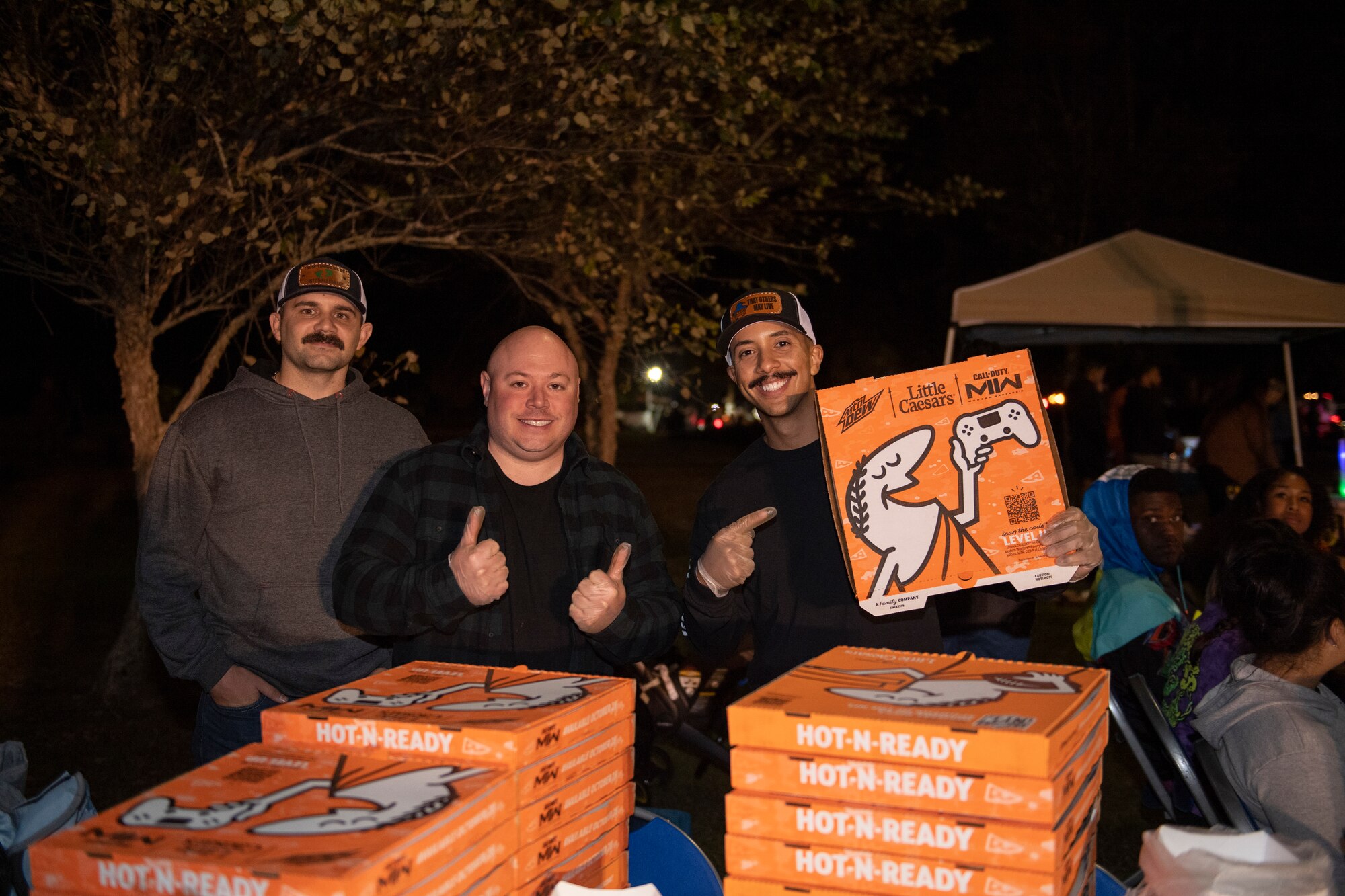 A photo of three guys posing with pizza boxes.